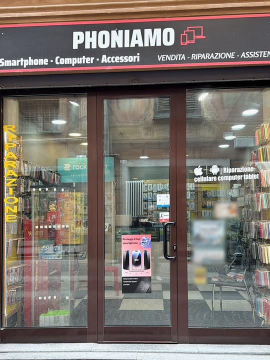 Entrance of the Phoniamo shop in Novi Ligure, with the sign "Smartphone · Computer · Accessori – Sales · Repair · Support"